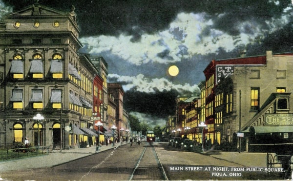 Historical postcard of Piqua, Ohio showing Main Street at night.