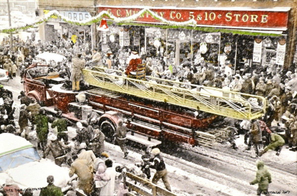 Historical photo of the Piqua Christmas parade in 1958. The photo features a fire engine with Santa riding on top. There are crowds of parade goers on both sides of the street. There is snow on the ground. The photograph has been colorized with red, green and yellow in the mostly black and white photo.