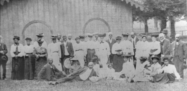 Historical black and white photograph of a group of thirty Black people at a gathering.